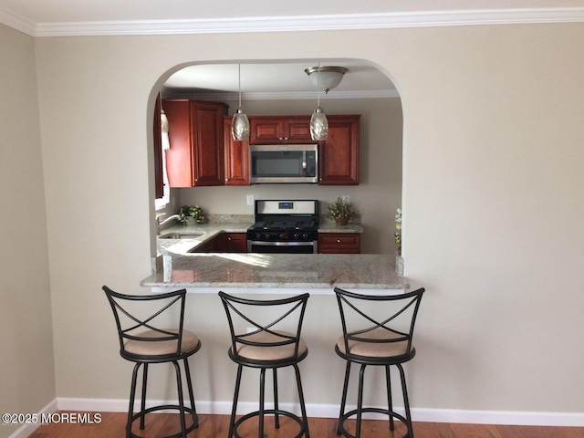 177 Pulaski Blvd, Toms River, NJ 08757 - kitchen featuring appliances with stainless steel finishes, a sink, arched walkways, light stone countertops, and a peninsula