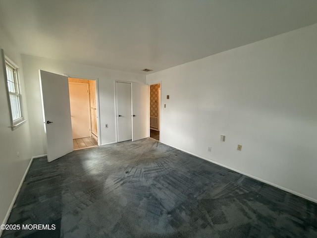 unfurnished bedroom with carpet, visible vents, and baseboards