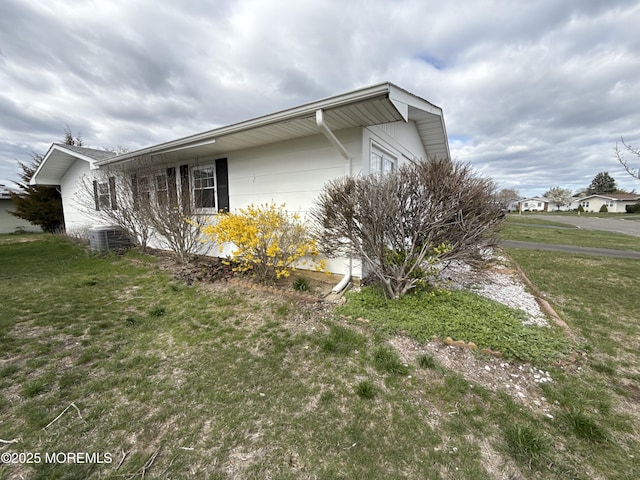 view of side of home with a yard and central AC