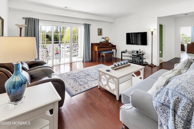 living room with crown molding, dark wood-style flooring, and visible vents