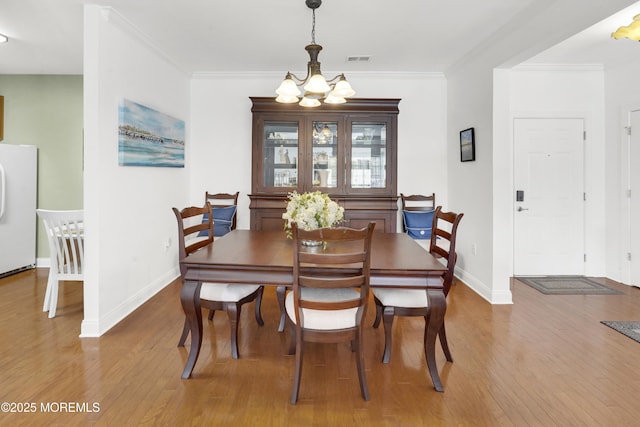 dining room with visible vents, baseboards, a notable chandelier, and hardwood / wood-style flooring