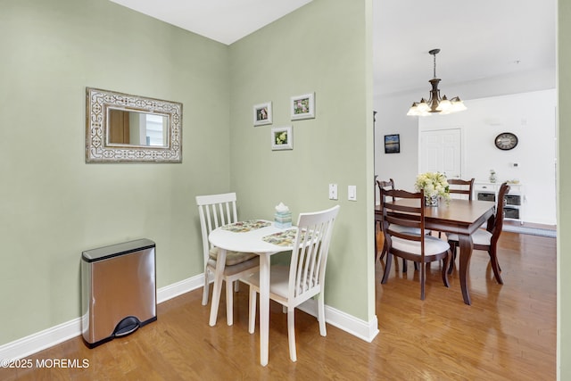 dining space with baseboards, wood finished floors, and a notable chandelier