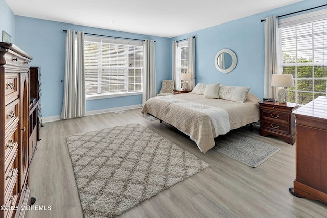 bedroom with baseboards, wood finished floors, and multiple windows