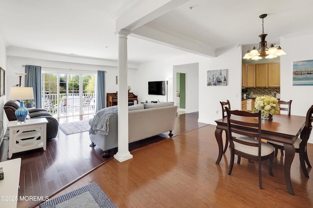 dining space featuring crown molding, decorative columns, wood finished floors, and a chandelier