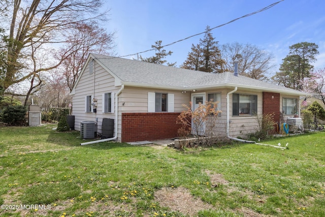 14B S Heron St, Manchester, NJ 08759 - view of front of home with cooling unit, brick siding, a front lawn, and roof with shingles