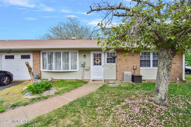view of front of property featuring a front yard, central AC, and brick siding