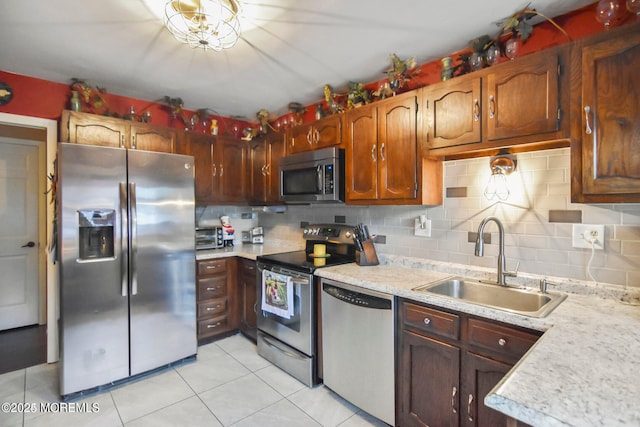 kitchen with light tile patterned floors, light countertops, decorative backsplash, stainless steel appliances, and a sink