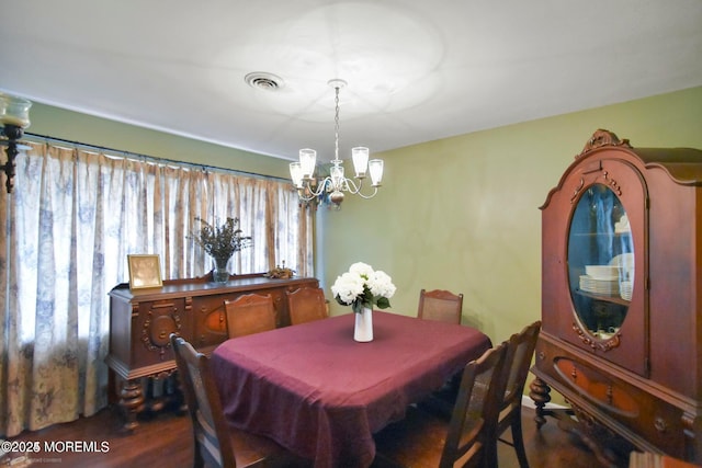 dining space with visible vents, an inviting chandelier, and wood finished floors