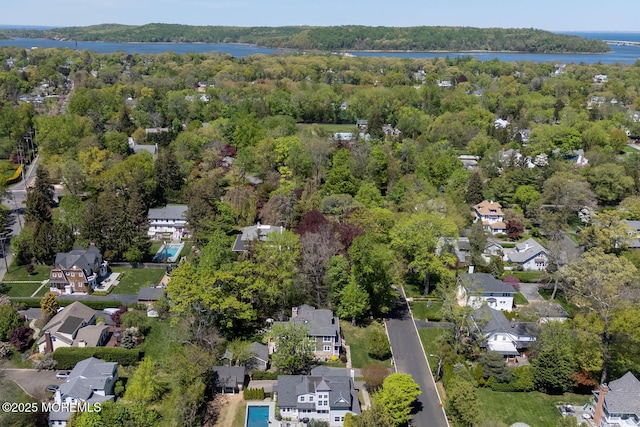 drone / aerial view with a residential view, a water view, and a forest view