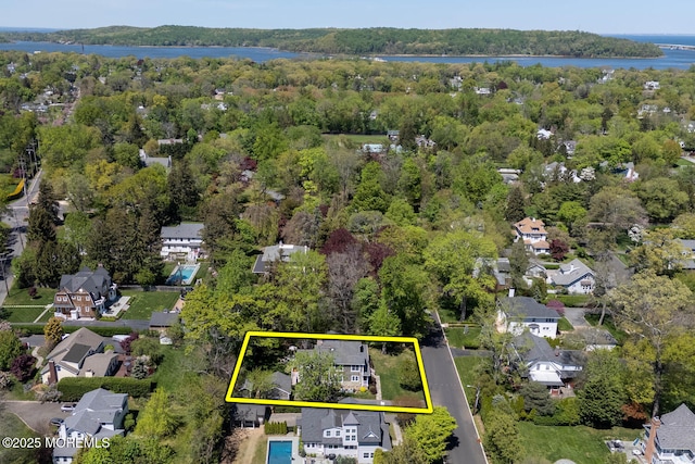 birds eye view of property with a wooded view, a water view, and a residential view