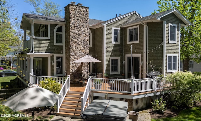 back of property with a chimney, a shingled roof, and a wooden deck