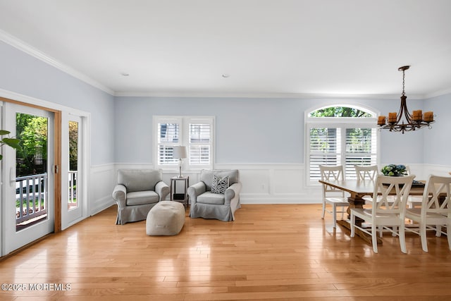 interior space featuring wainscoting, a notable chandelier, ornamental molding, and light wood-type flooring