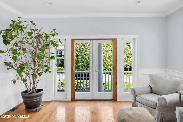 entryway with a healthy amount of sunlight, ornamental molding, wood-type flooring, and visible vents