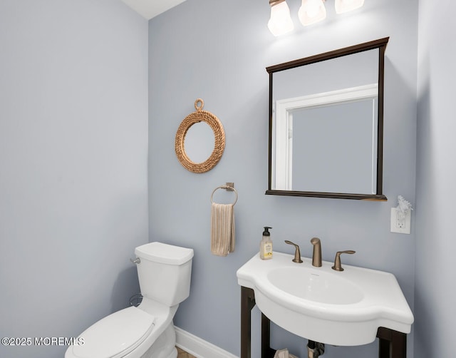 bathroom featuring a sink, baseboards, and toilet