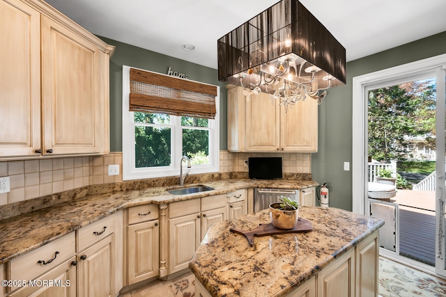 kitchen with a sink, light stone counters, stainless steel dishwasher, and backsplash