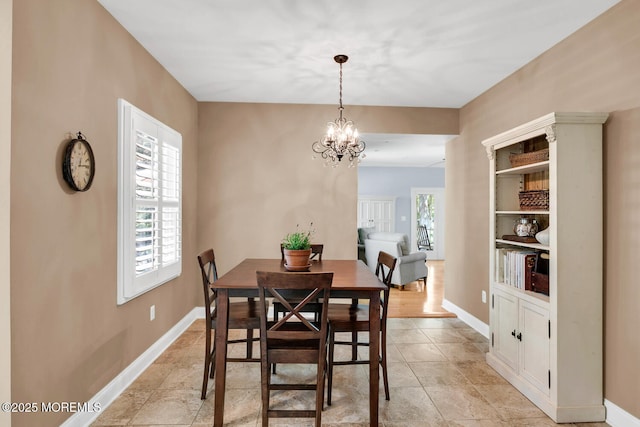 dining room featuring baseboards and a notable chandelier