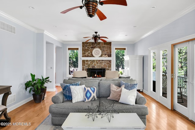 living room with ceiling fan, a fireplace, light wood-style floors, baseboards, and visible vents