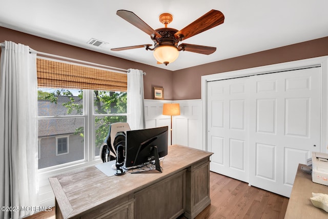 office featuring ceiling fan, light wood-style flooring, and visible vents