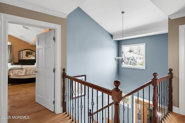 hallway with baseboards, vaulted ceiling, wood finished floors, and an upstairs landing