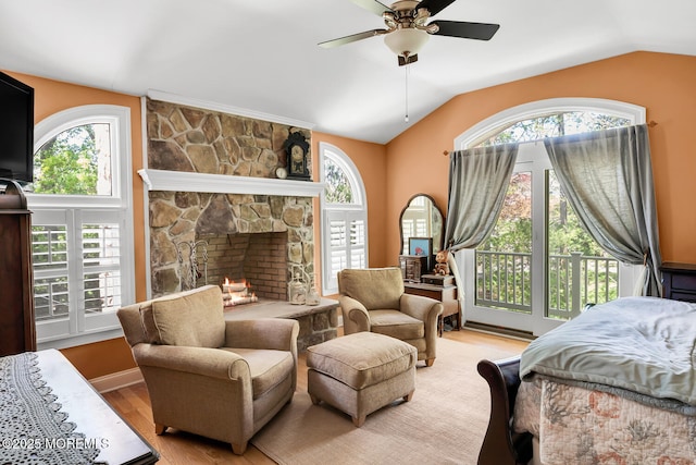bedroom featuring access to outside, vaulted ceiling, a stone fireplace, and wood finished floors