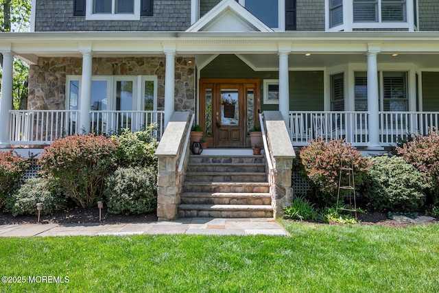 property entrance with a porch, a yard, and stone siding