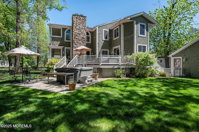 back of property with a wooden deck, a chimney, a yard, and a patio area
