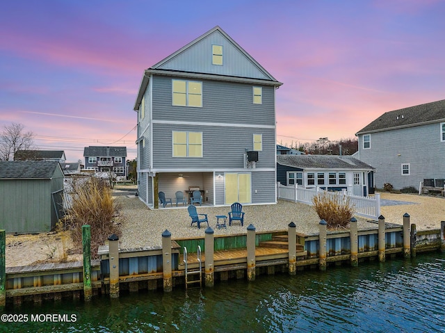 211 Pine Dr, Bayville, NJ 08721 - back of property at dusk featuring a shed, a deck with water view, an outdoor structure, and fence