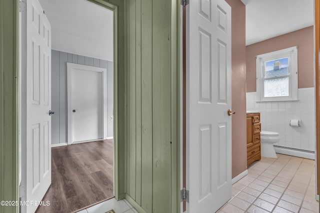 37 Scarborough Pl, Toms River, NJ 08757 - corridor featuring light tile patterned floors, a baseboard radiator, tile walls, and a wainscoted wall
