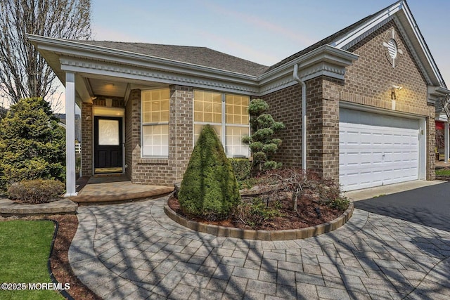 view of front of property featuring driveway, a garage, brick siding, and a shingled roof
