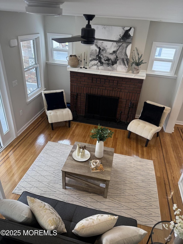 living room with baseboards, wood finished floors, a healthy amount of sunlight, and a fireplace