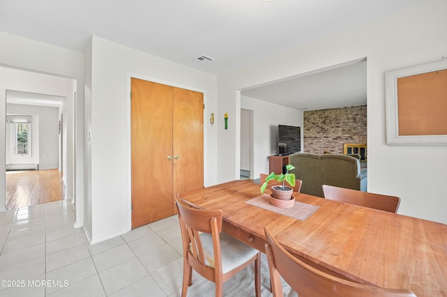 dining space with visible vents, a fireplace, and light tile patterned floors