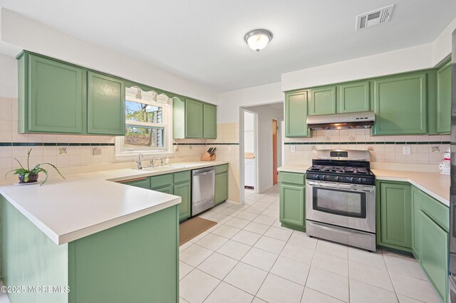 kitchen with under cabinet range hood, visible vents, a sink, green cabinets, and appliances with stainless steel finishes