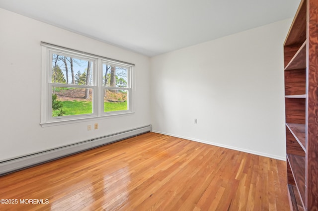 spare room with baseboard heating, baseboards, and light wood-type flooring