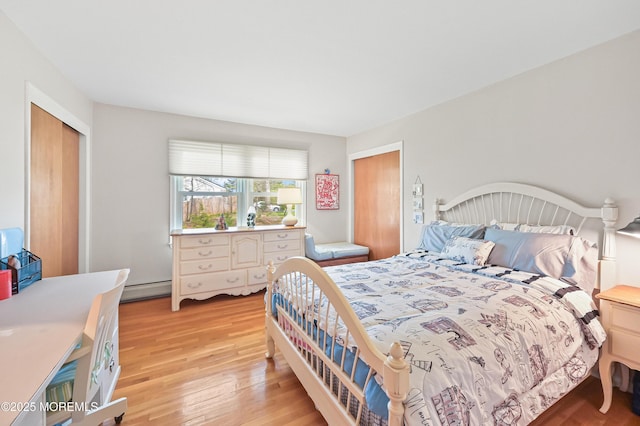 bedroom featuring baseboard heating, light wood-style floors, and a closet