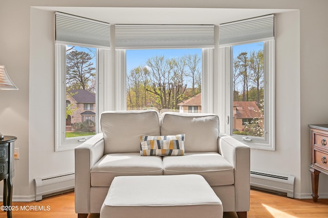 living area with a baseboard radiator, light wood-style floors, plenty of natural light, and baseboard heating