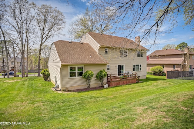 rear view of property featuring a chimney, fence, a shingled roof, a deck, and a yard