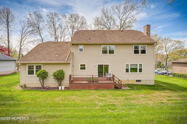 rear view of property featuring a chimney, roof with shingles, a deck, and a lawn