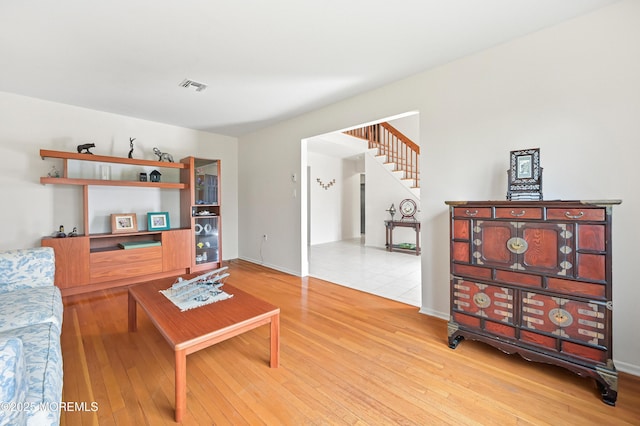 living room with baseboards, wood finished floors, visible vents, and stairs