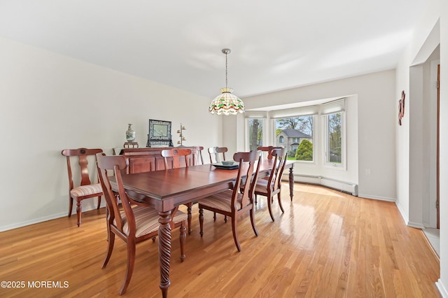 dining room with a baseboard heating unit, light wood-style floors, and baseboards