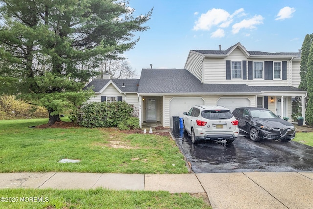 view of front facade with a garage, driveway, a shingled roof, and a front yard