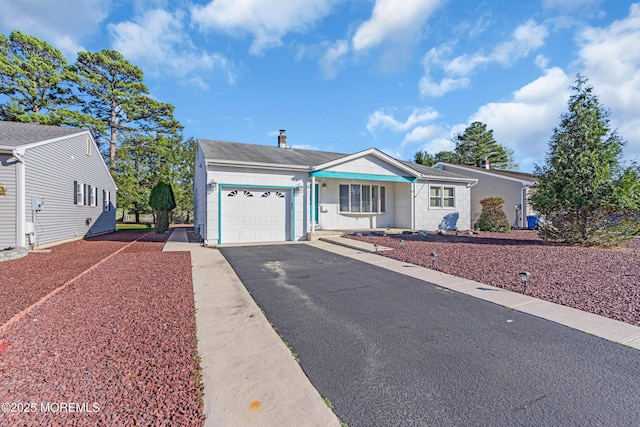 ranch-style home featuring a garage, roof with shingles, and aphalt driveway