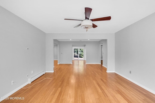 spare room with a baseboard radiator, light wood-style floors, baseboards, and ceiling fan