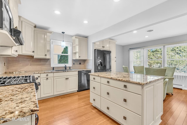 kitchen featuring a center island, a sink, a baseboard heating unit, black appliances, and visible vents