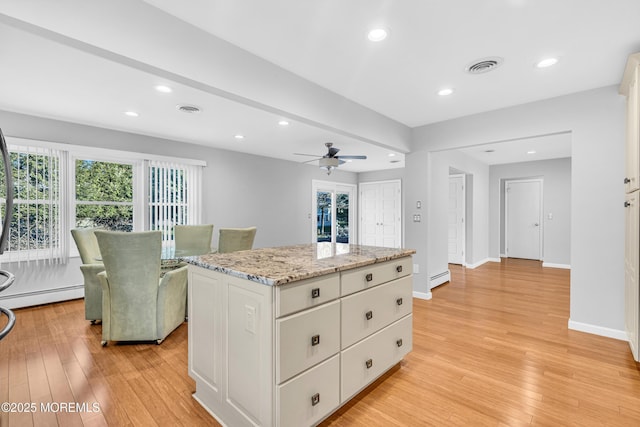 kitchen featuring light wood finished floors, visible vents, a ceiling fan, a baseboard heating unit, and a baseboard radiator