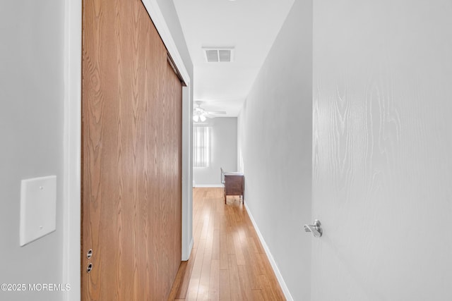 corridor with baseboards, light wood finished floors, and visible vents
