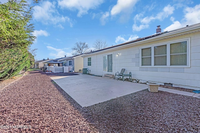 back of property with central air condition unit, a chimney, and a patio area