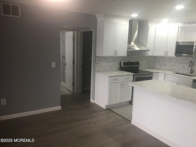 kitchen featuring a sink, visible vents, recessed lighting, wall chimney range hood, and appliances with stainless steel finishes