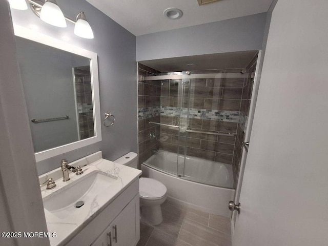 bathroom featuring toilet, tile patterned floors, vanity, and bath / shower combo with glass door