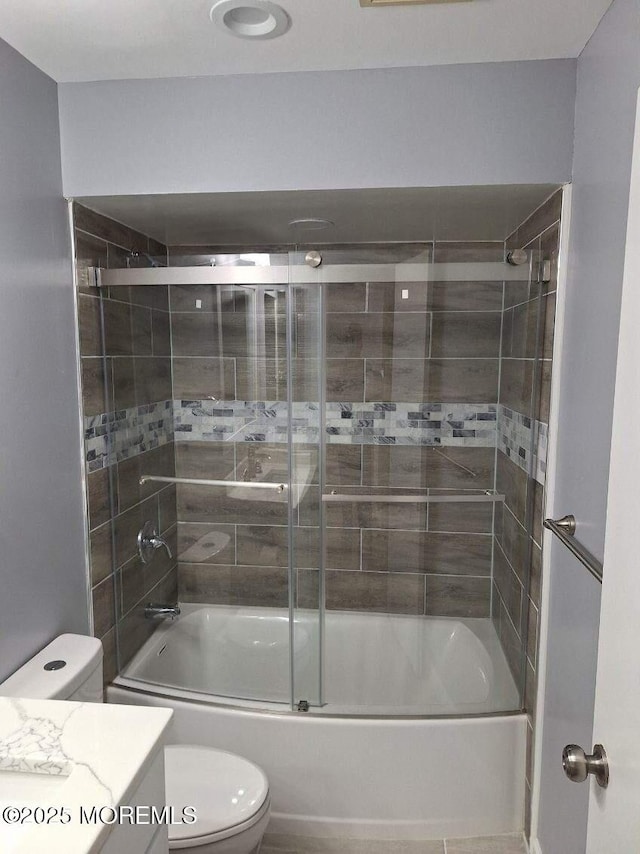bathroom with combined bath / shower with glass door, vanity, and toilet