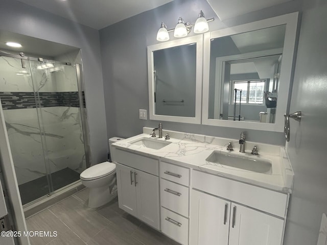bathroom with toilet, a sink, a marble finish shower, and double vanity
